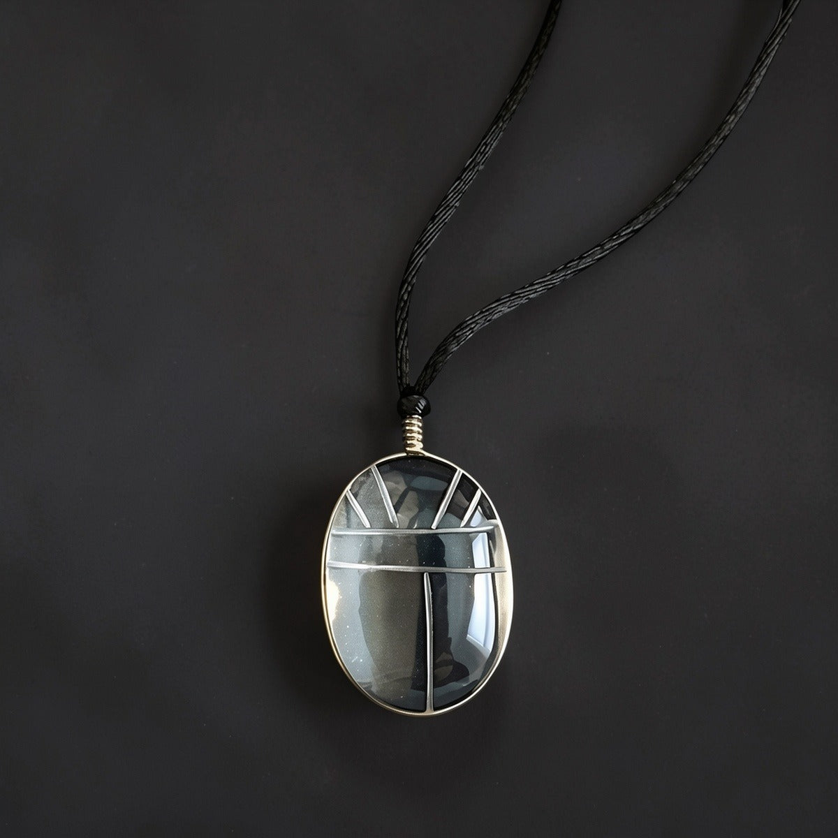 Hand-carved clear quartz Scarab pendant wrapped in Sterling silver wire, suspended from a 26-inch black silk cord with silver teardrop accents.