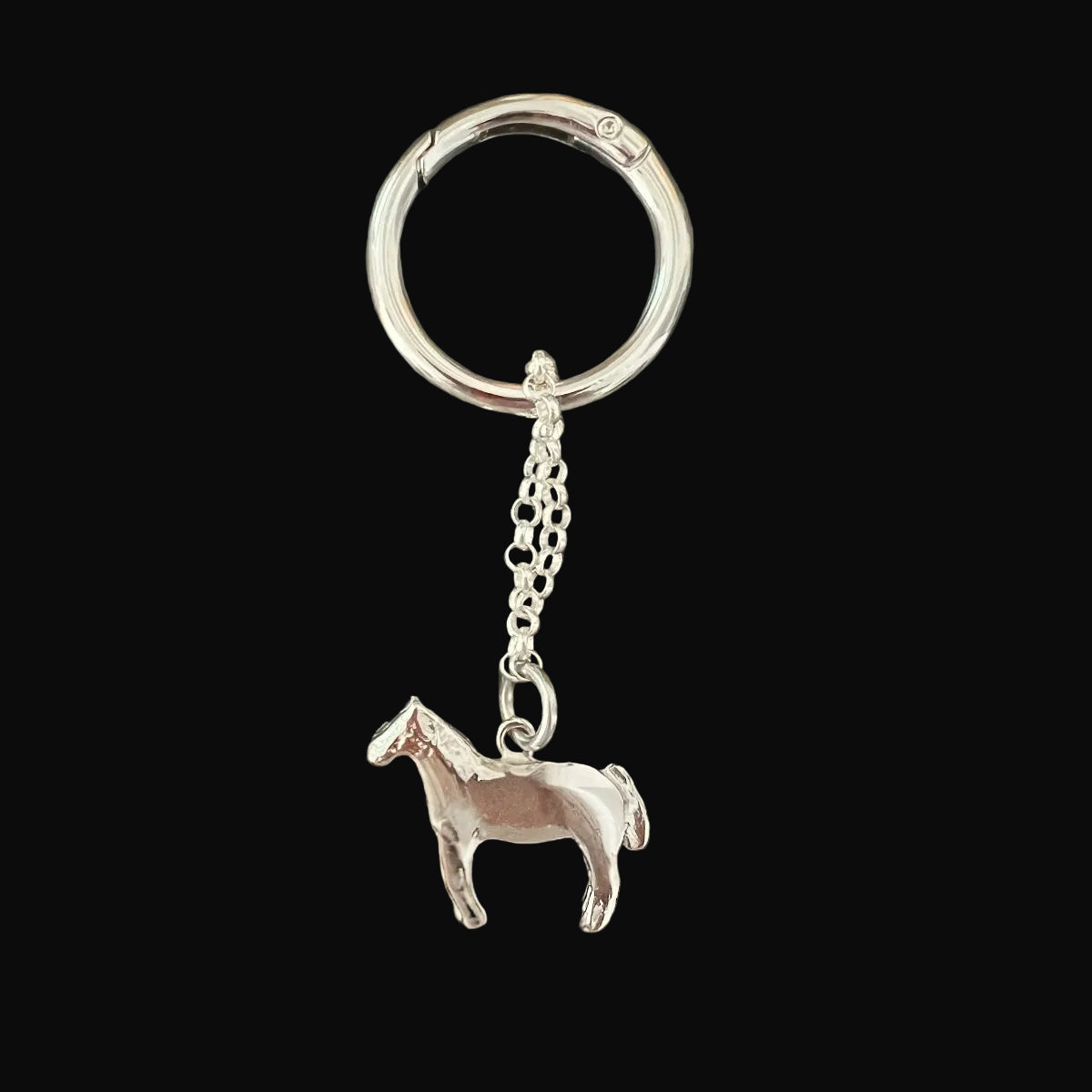 Silver horse-shaped keychain on a dark surface