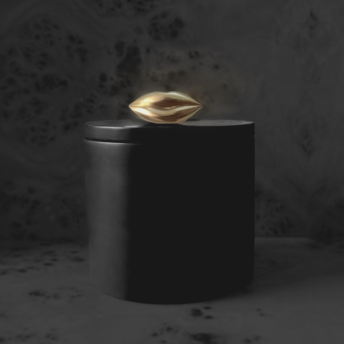 Black candle vessel with a gold, kiss lips

