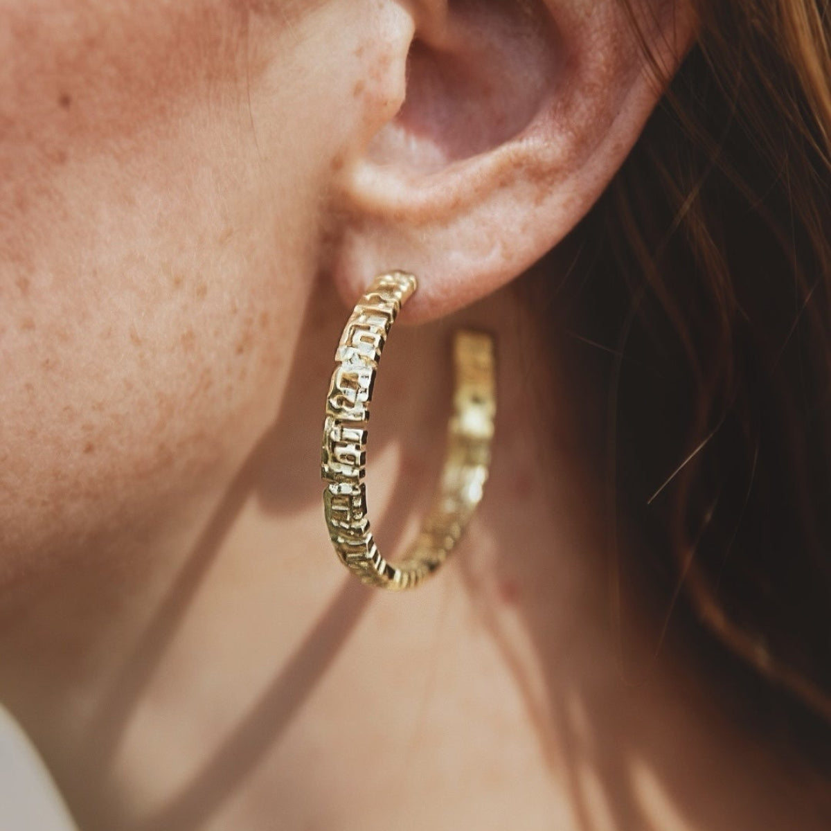 Lucca large gold hoop earrings with a bold modernist sculptural silhouette. Lightweight luxury designer hoop earrings.