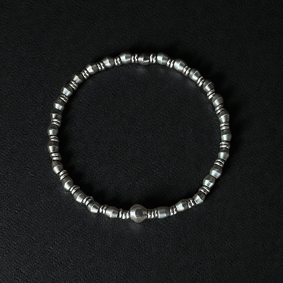Men's luxury silver metal bead bracelet featuring faceted and donut-shaped beads on a comfortable stretch cord.