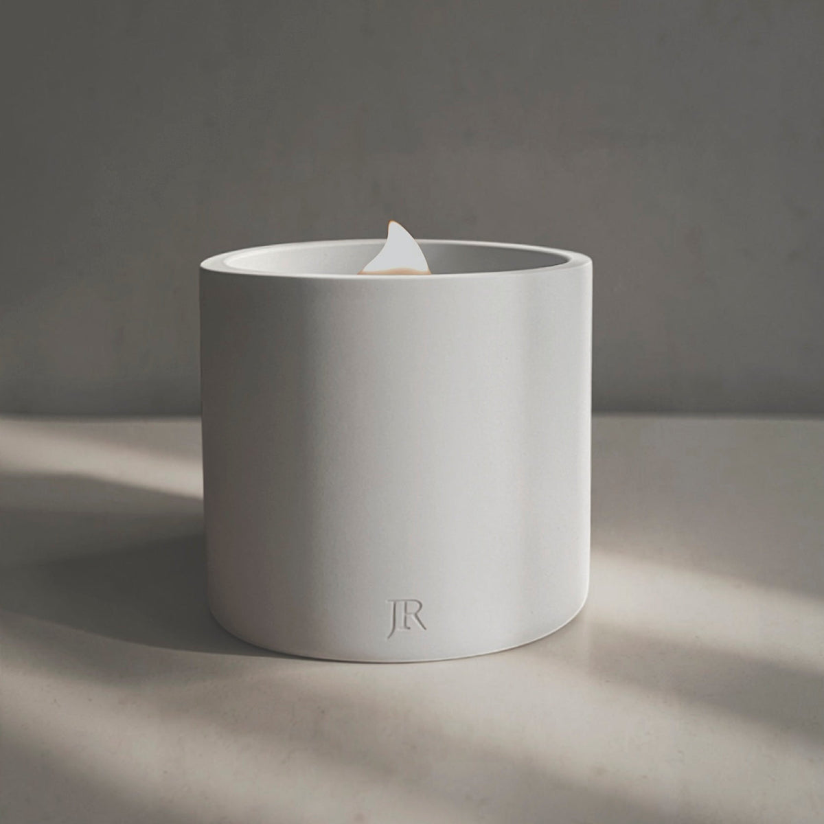 Luxury hand-poured scented candle in a sculptural white concrete vessel with essential oils and a crackling wooden wick.