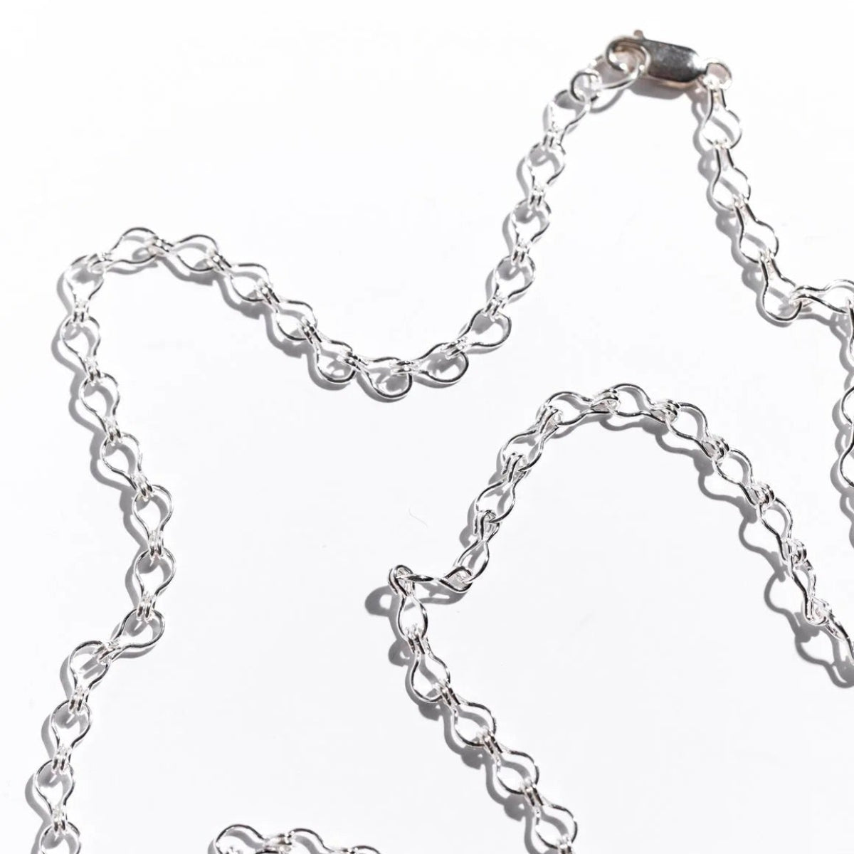 Luxury men's silver ladder chain necklace with structured links and modern architectural design.