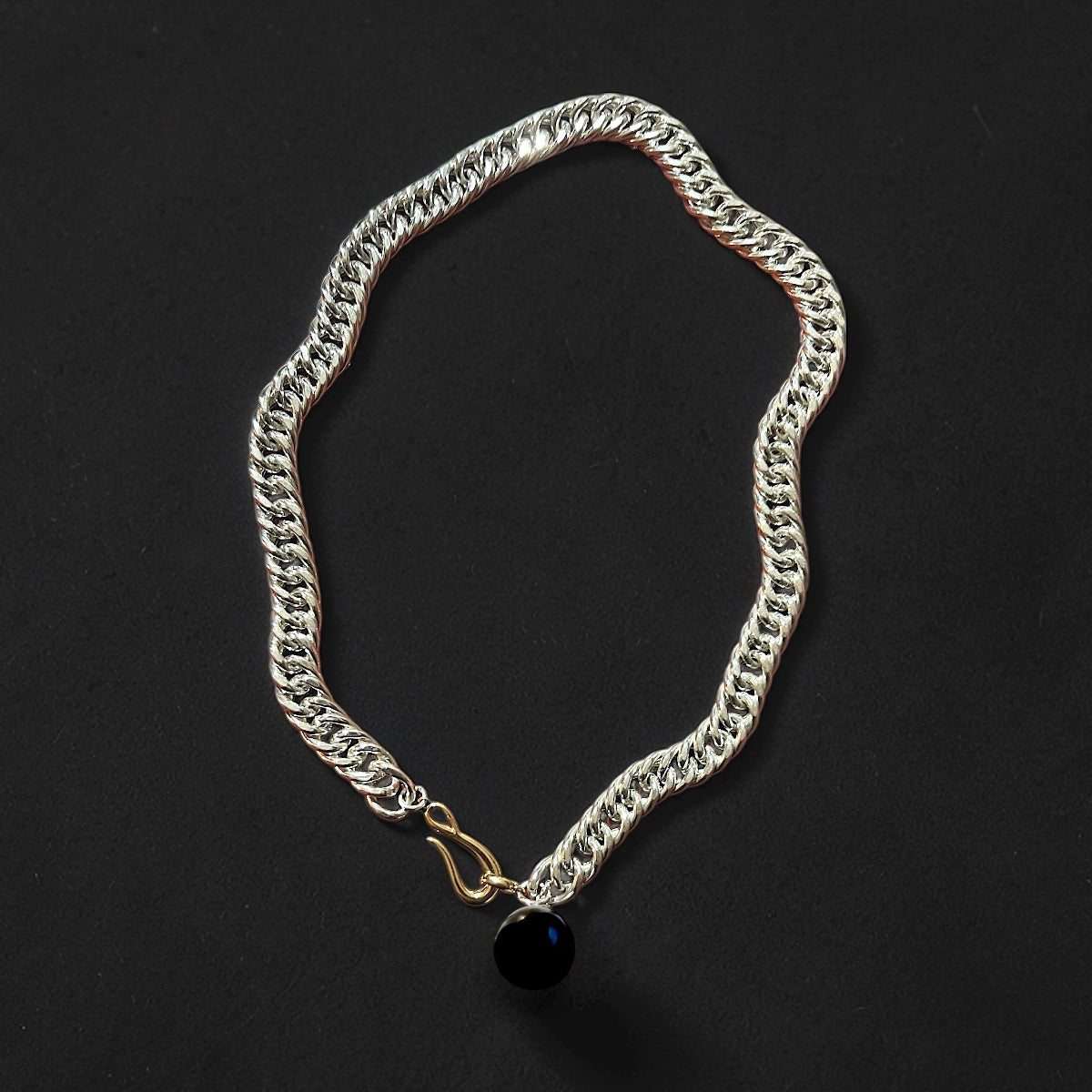 A chunky silver chain necklace featuring an onyx orb.