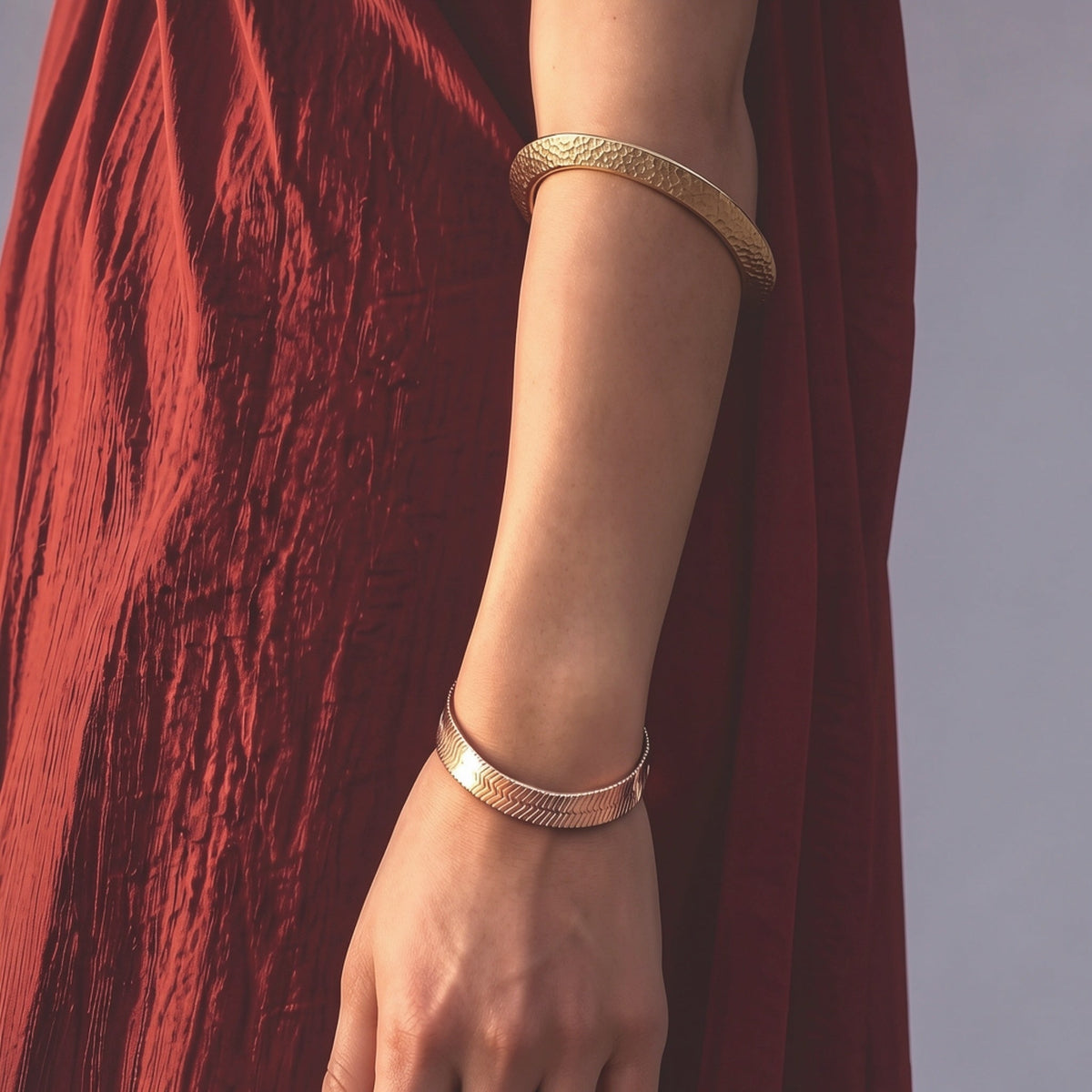 Wedge hammered gold-plated statement bangle worn on the arm, featuring a sculptural wide silhouette and softly polished gold texture.