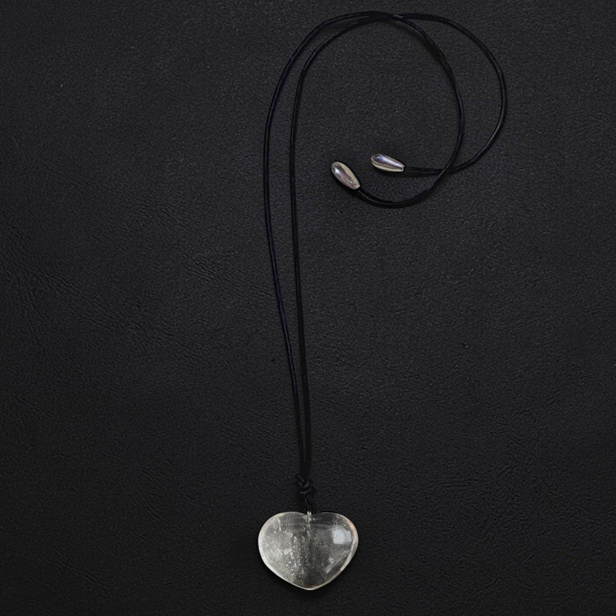 Big Heart rock crystal quartz necklace with hand-carved heart pendant on black leather cord, finished with sterling silver teardrop accents, worn long or as a choker.