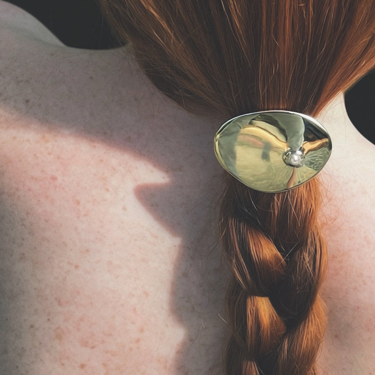 Cirque hair tie in high polish bronze with freshwater pearl accent, sculptural modern hair accessory with strong elastic band