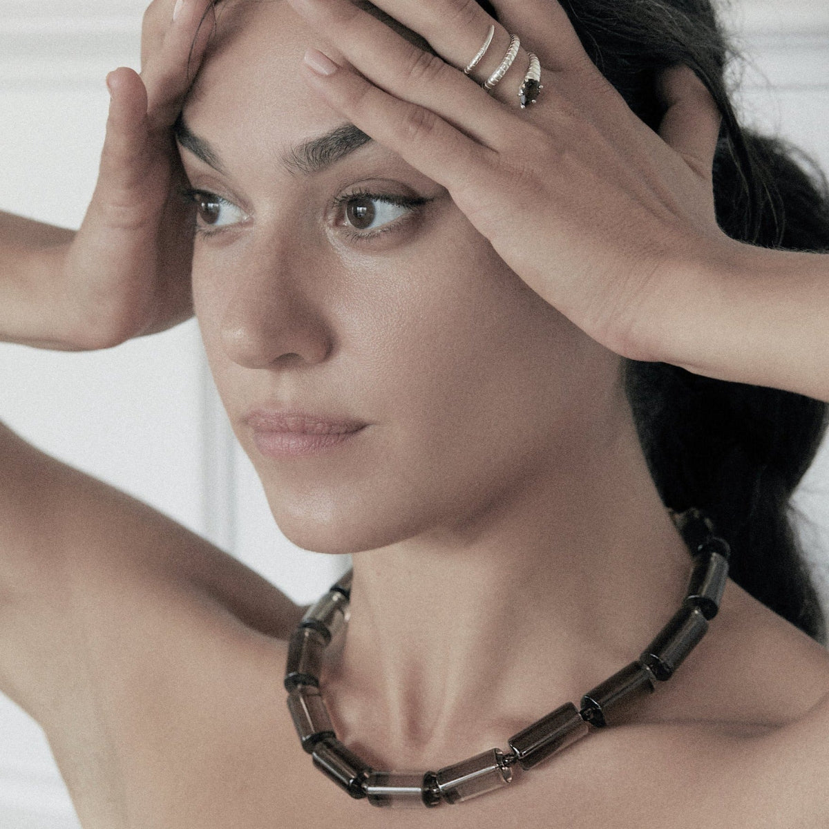 A model wearing a sterling silver smoky quartz snake ring and large pillar necklace.