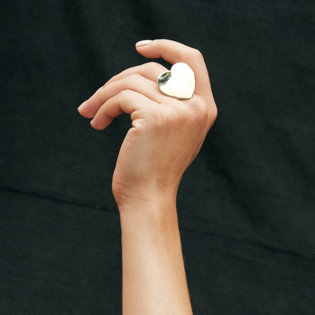 Minimalist still life of a gold-plated heart ring, embodying modern romance and timeless form
