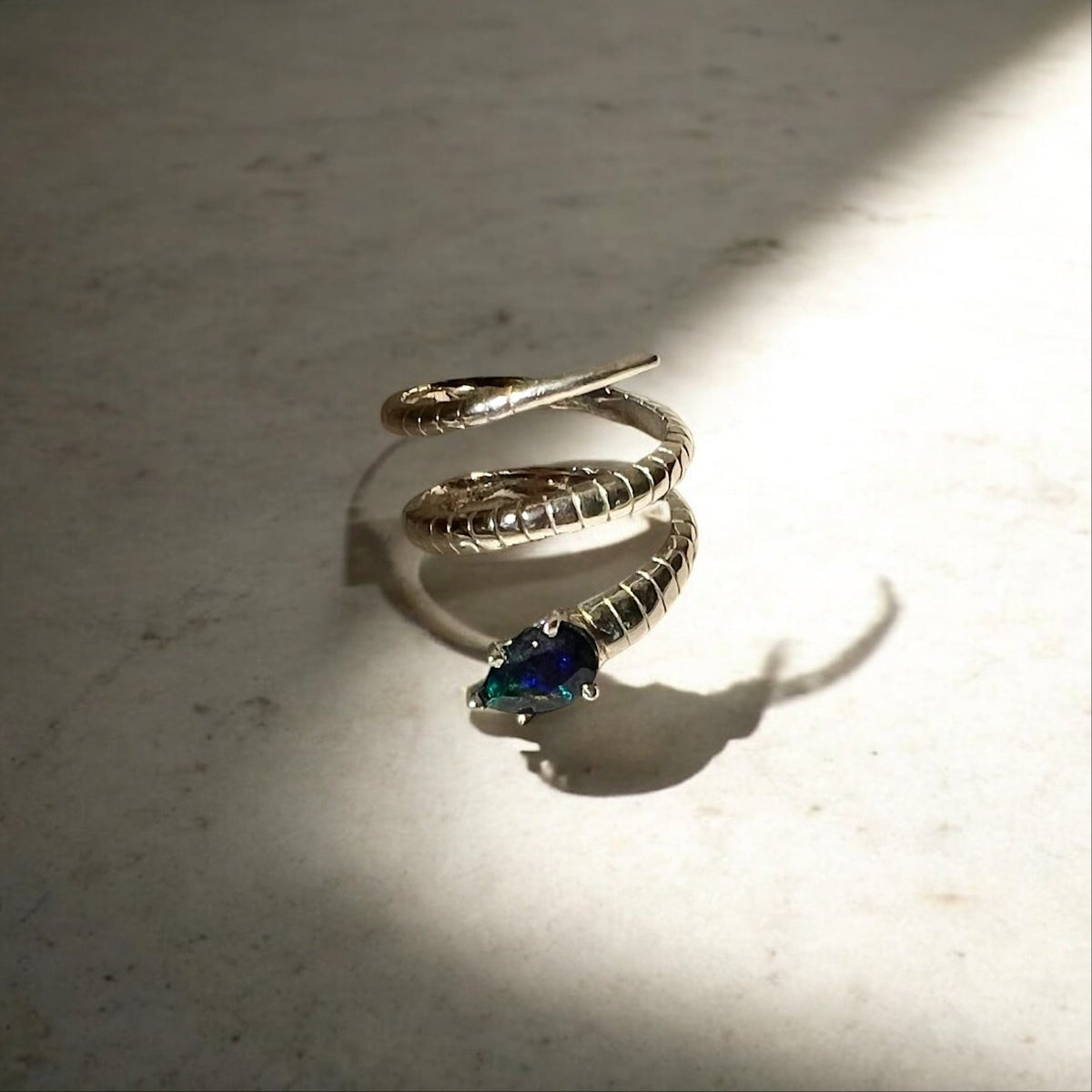 A silver snake ring with a black opal.