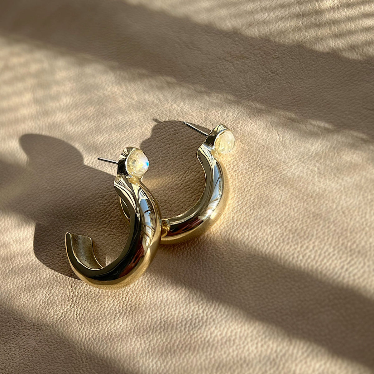 Rainbow moonstone hoop earrings in a high-polished gold-plated setting. Lightweight luxury earrings and modern heirloom jewelry.