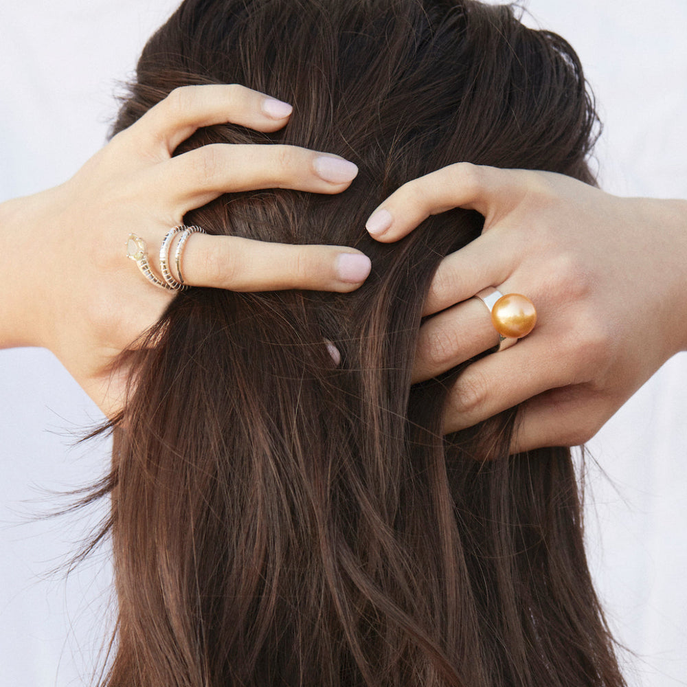 A model wearing a sterling silver snake ring with lemon quartz wrapped around her finger and champagne pearl ring.